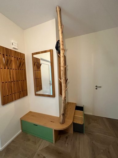 Holzbank mit Ablageflächen, Spiegel und einem vertikalen Holzstamm an der Wand.